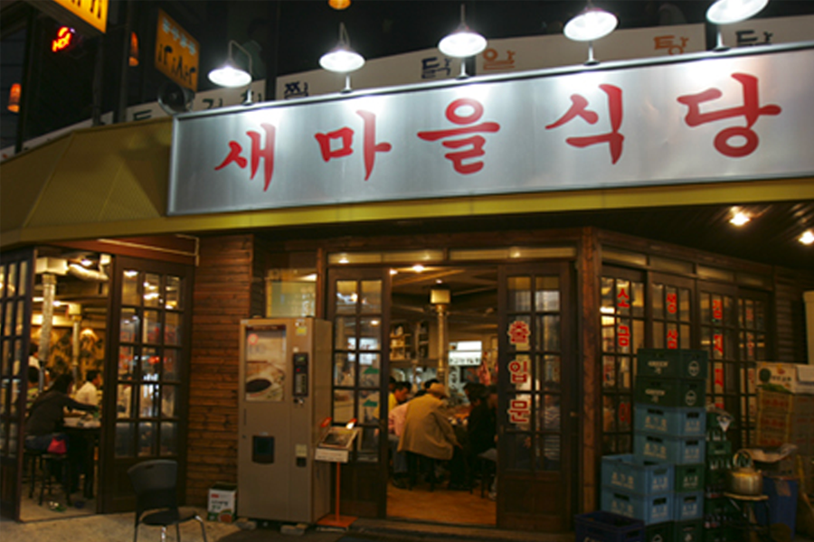 新村食堂餐廳入口夜景,提供經濟實惠的韓式烤肉,吸引眾多顧客入內享用。