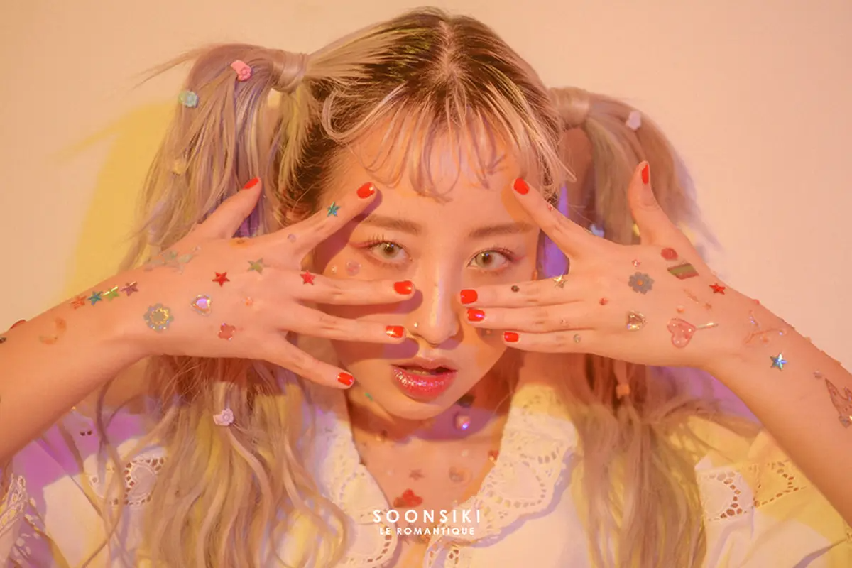 A model showcasing colorful, trendy stickers and intricate nail art, reflecting Korean beauty and fashion trends.