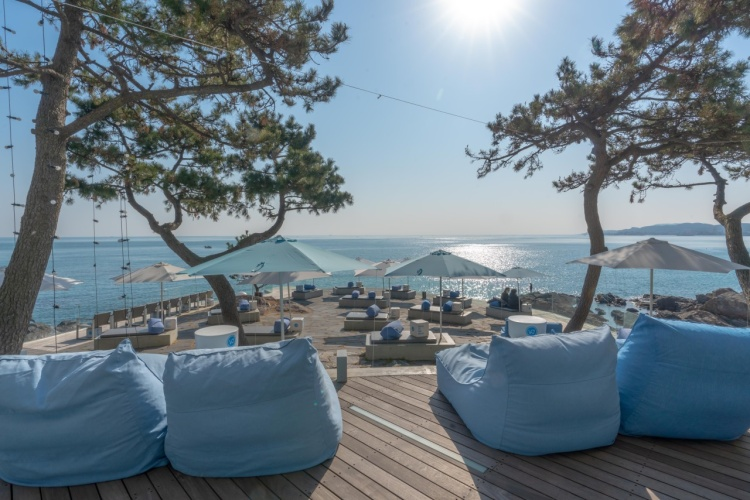 Gemütliche Sitzecken auf der Terrasse des Waveon Coffee mit Blick auf das Meer