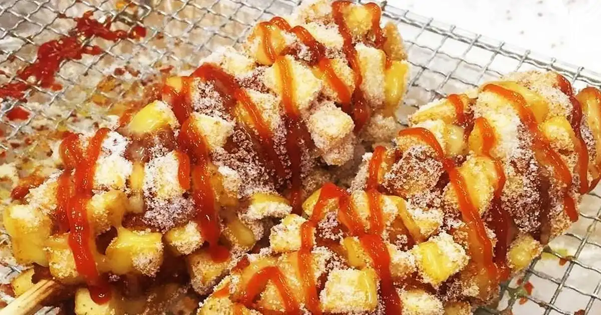 韩式热狗特写，表面撒有糖粉和番茄酱，咬了一口。