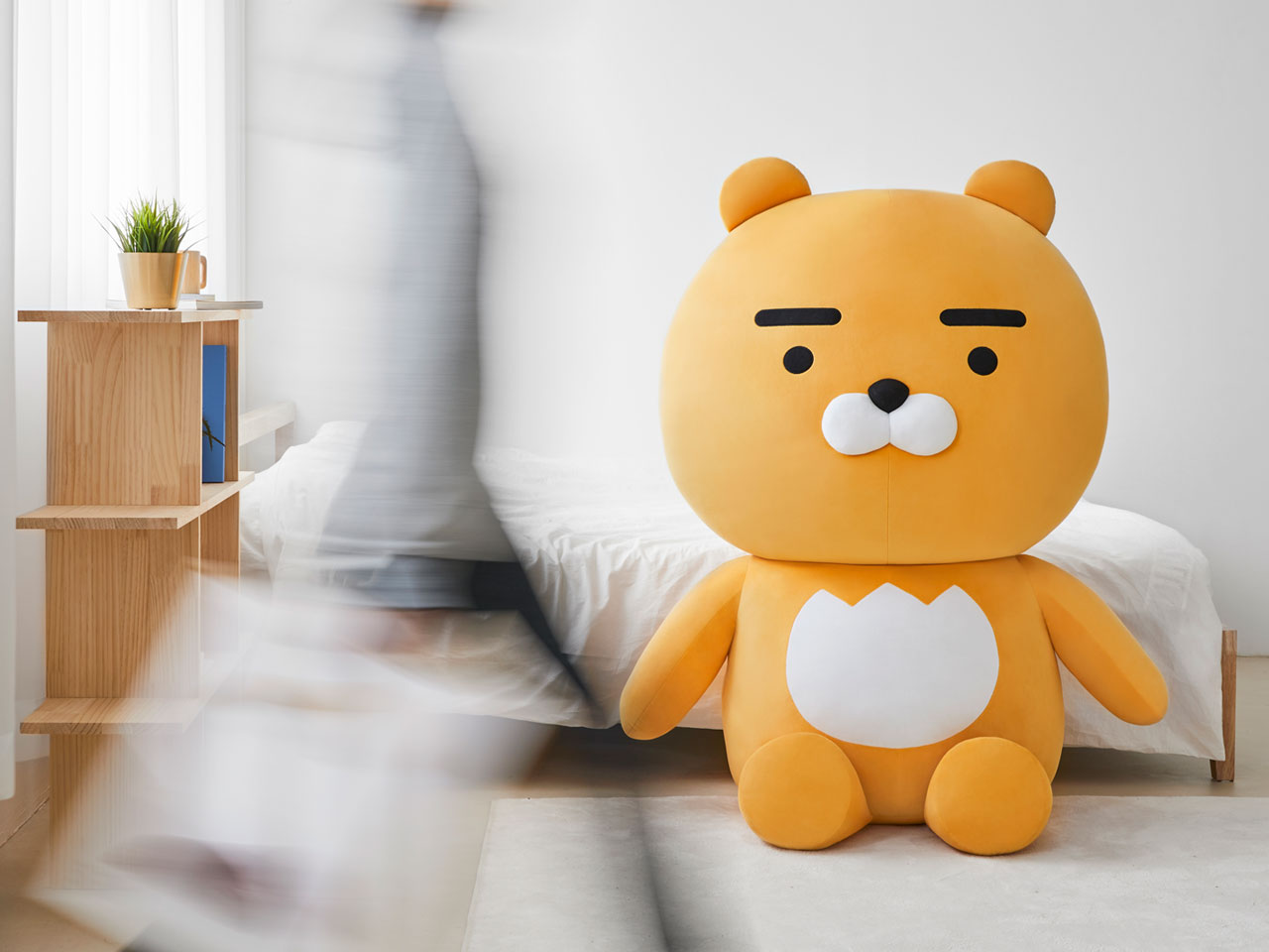 巨型 Ryan 布偶以其龐大的體積矗立在床邊，成為一個懶人椅選項，為房間增添些許俏皮感。
