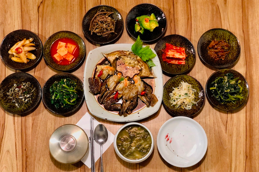 滿桌的韓式小菜，中心擺著一道醬蟹，色彩豐富的韓式料理。