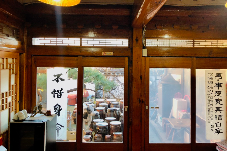 視角從室內望向庭院，庭院內放置著傳統韓式醬缸。