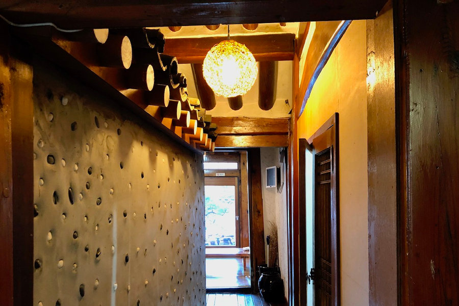 通往庭院的走廊，牆壁裝飾著韓國傳統的瓦片和燈具。