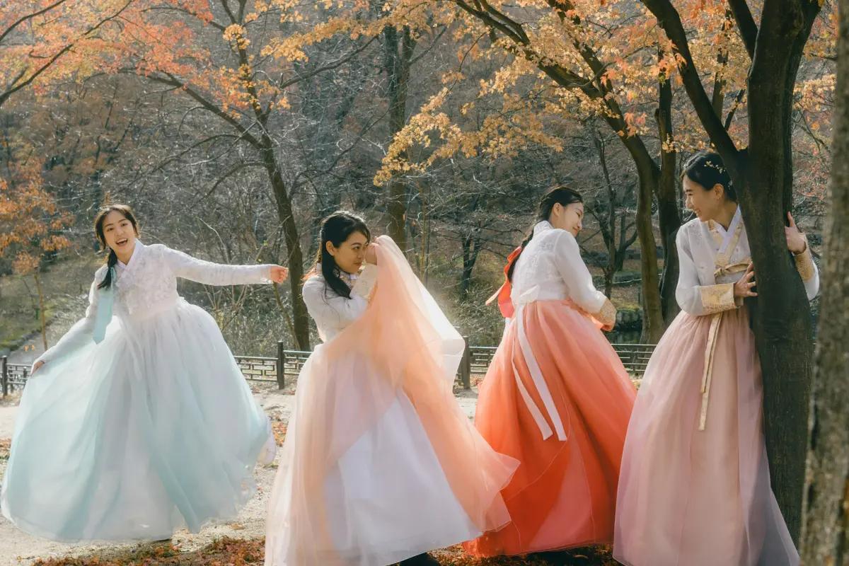 韓國傳統建築前兩位女子穿著顏色柔和的韓服並笑著互動