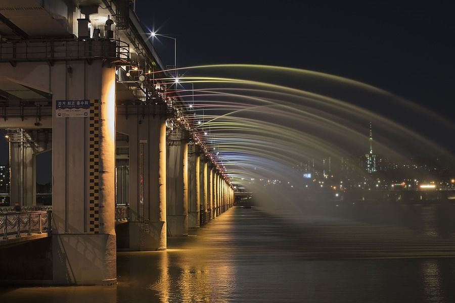 夜间的盘浦大桥彩虹喷泉，弧形的水柱在黑色的夜空下划出一道道绚丽的虹。
