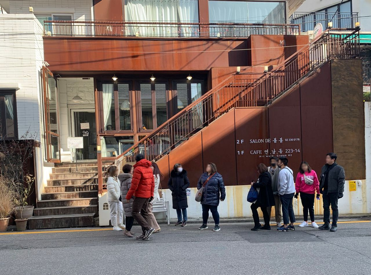 延南洞223-14咖啡廳的外觀，有數人排隊等待進入，建築展示獨特的現代設計。