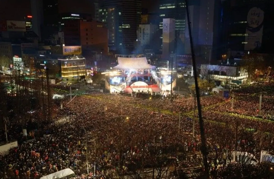 首爾鐘閣站除夕之鐘跨年活動的夜晚人群。圖片展示成千上萬的觀眾聚集在鐘閣站前，慶祝韓國傳統的跨年儀式，充滿活力和節慶氣氛。