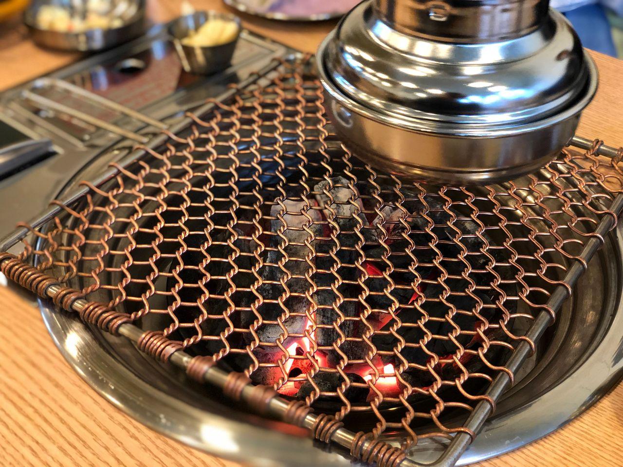 焼肉用の網が置かれ、準備が整った焼肉グリル。金網は綺麗に整えられ、火が見える。