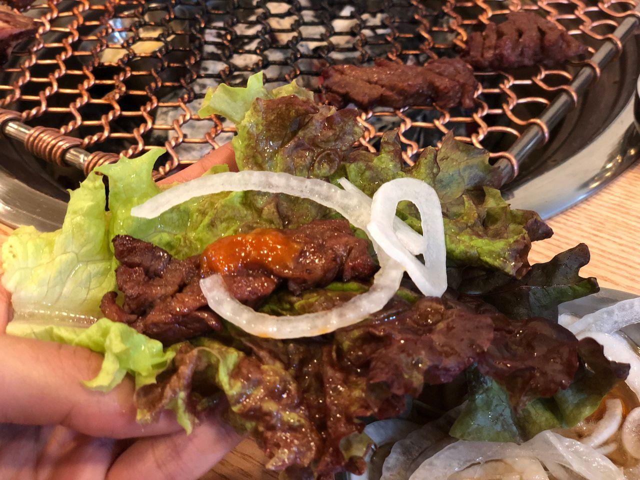 レタスに包んだ韓国焼肉サムギョプサルスタイル。カルビがジューシーで美味しそうに見える。