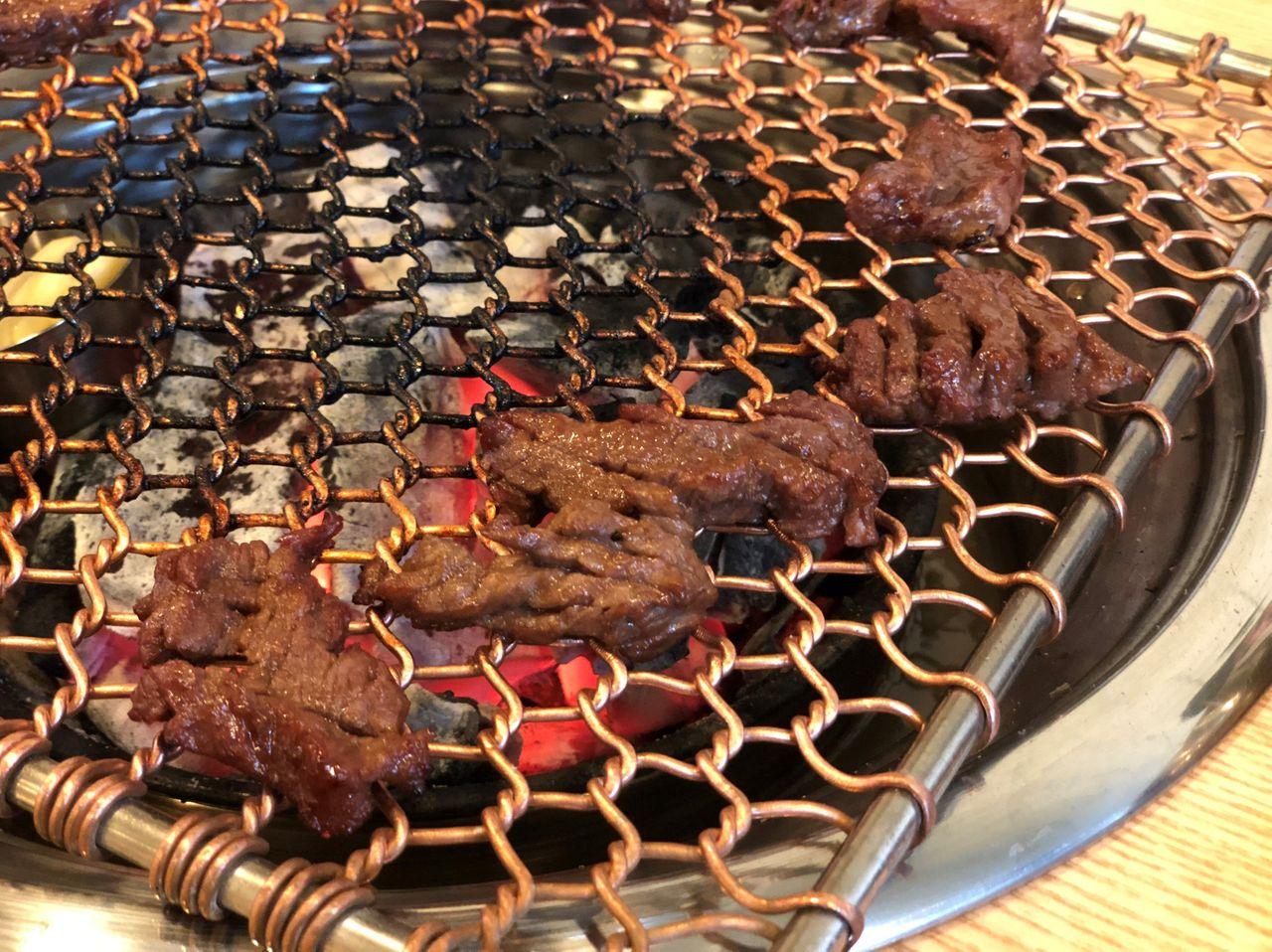 五道麵屋で焼肉グリルの上で焼かれているカルビ。じゅうじゅうと音を立てて美味しそう。