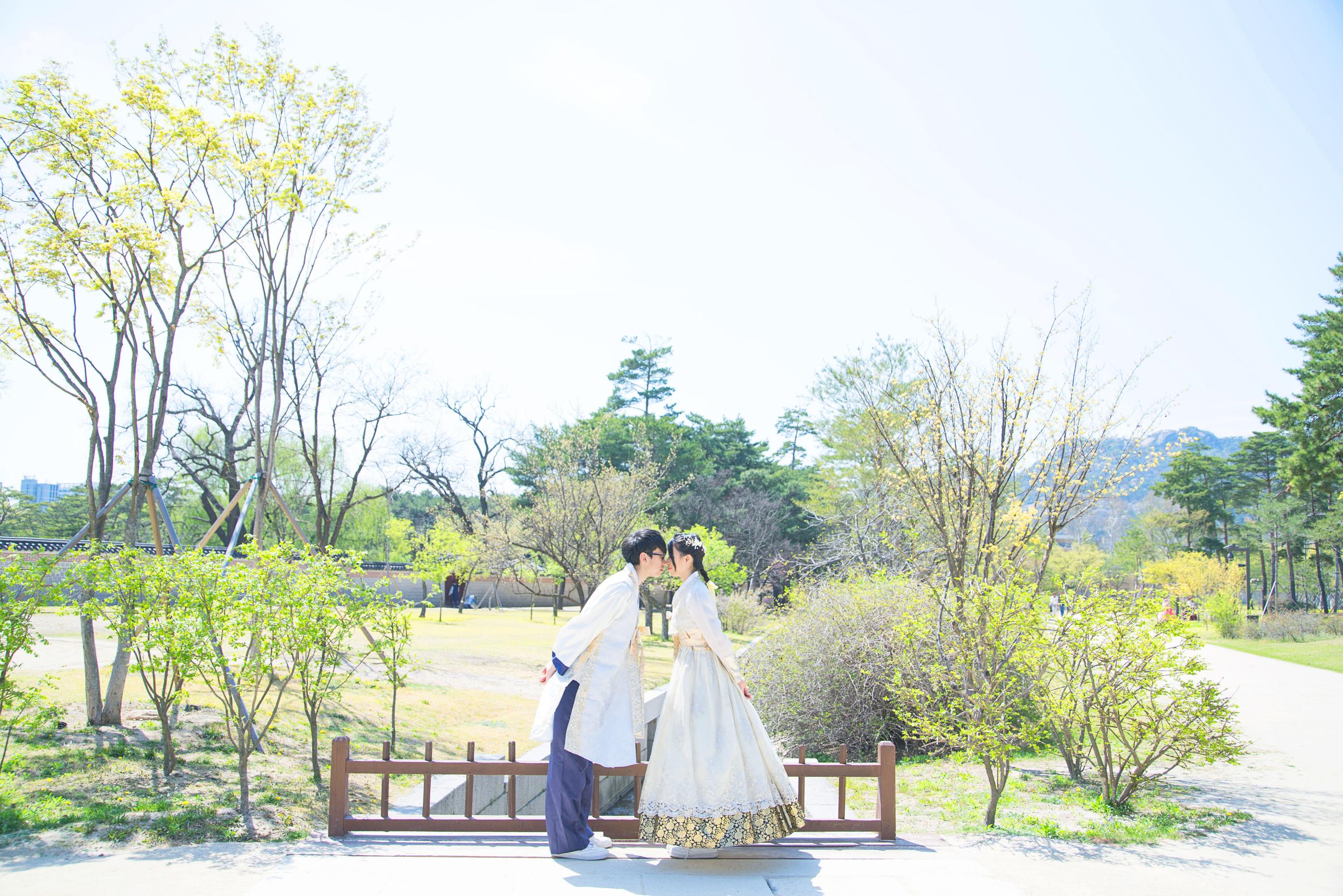 韓服を着たカップルが庭で優雅にポーズを取る様子