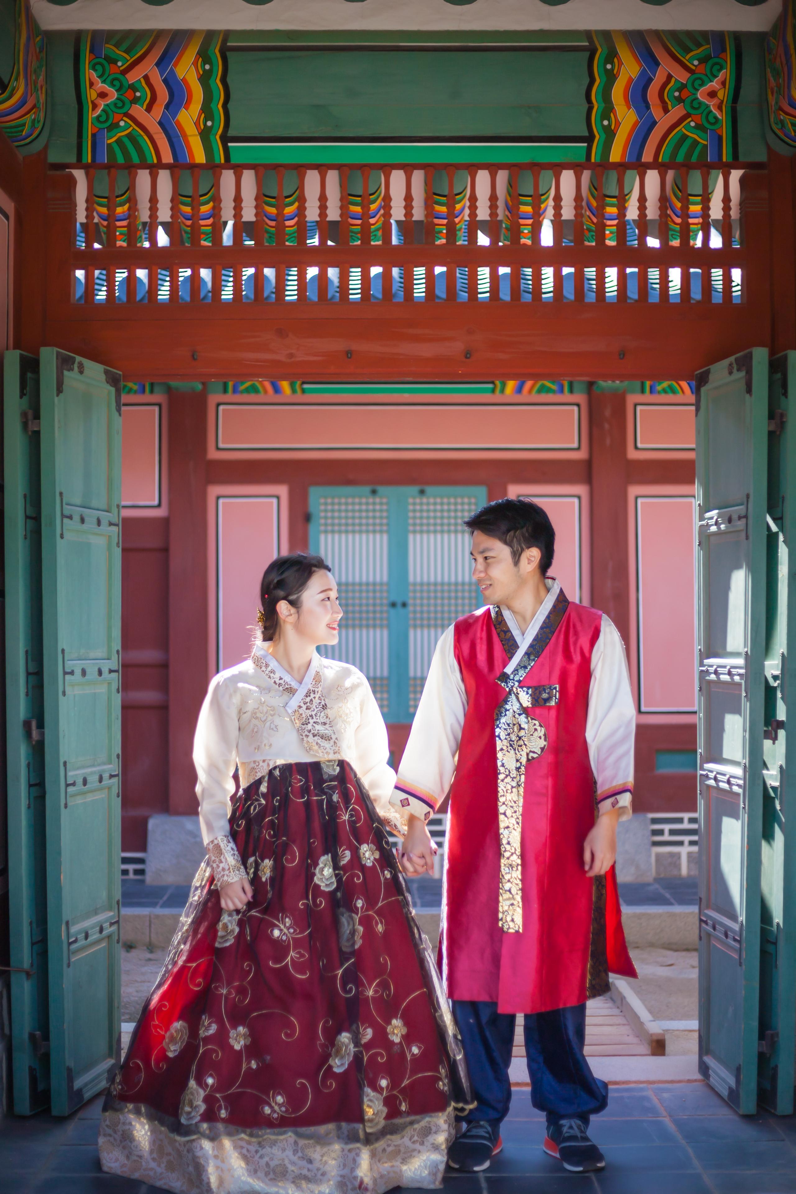 紅葉の背景で韓服を着た夫婦がハートを作る瞬間