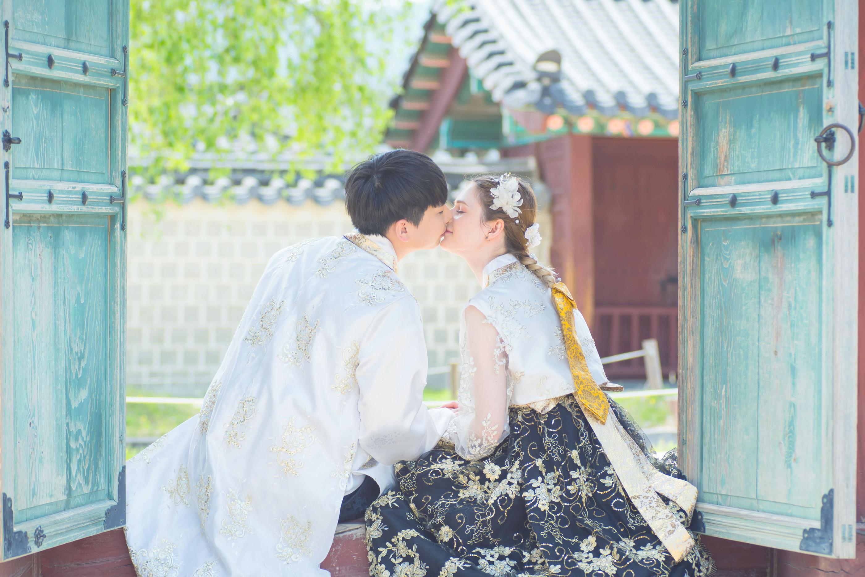 韓服を着たカップルが韓国の伝統的な家の庭でくつろぐ瞬間