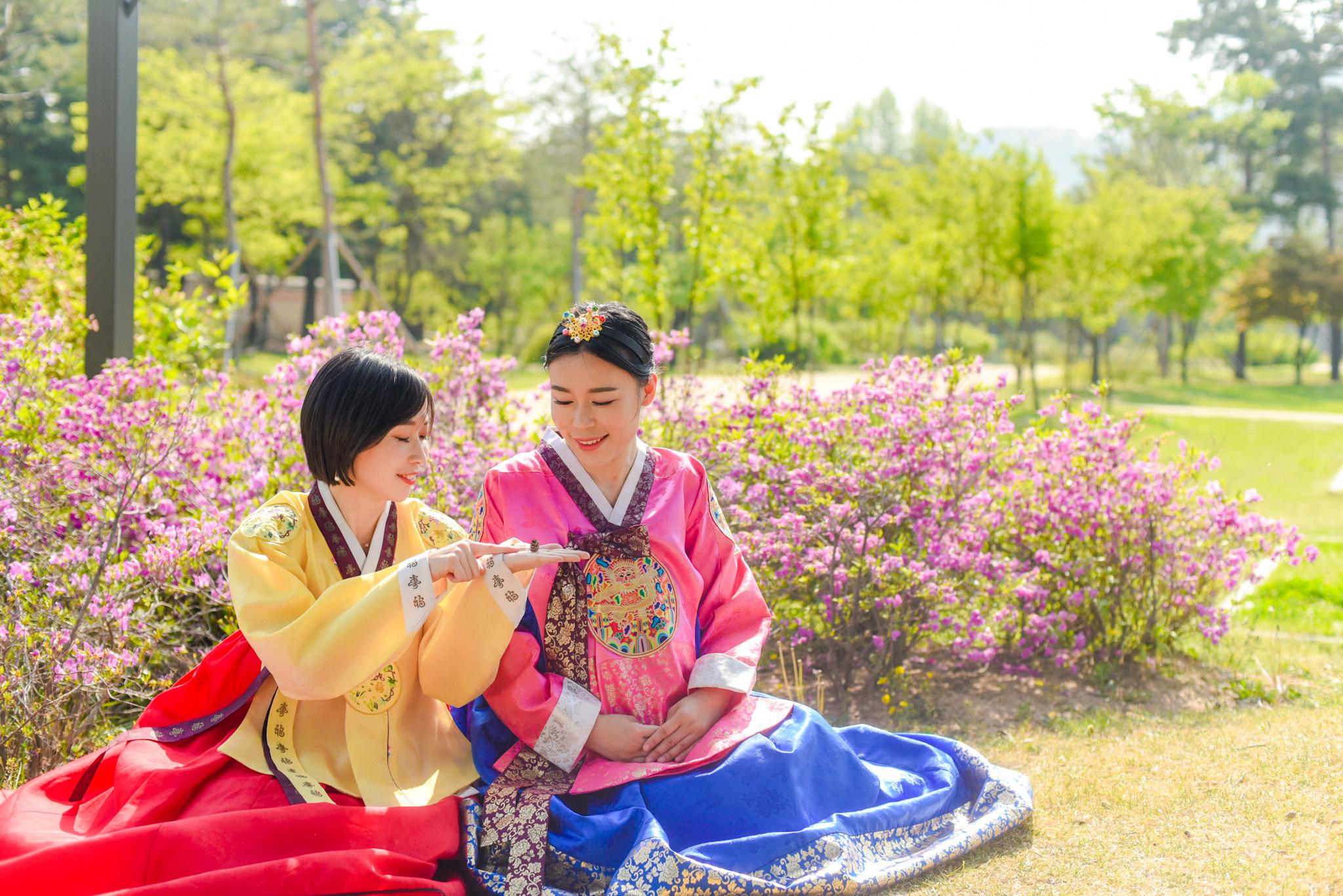 韓服を着た二人が公園で楽しそうに座っている風景