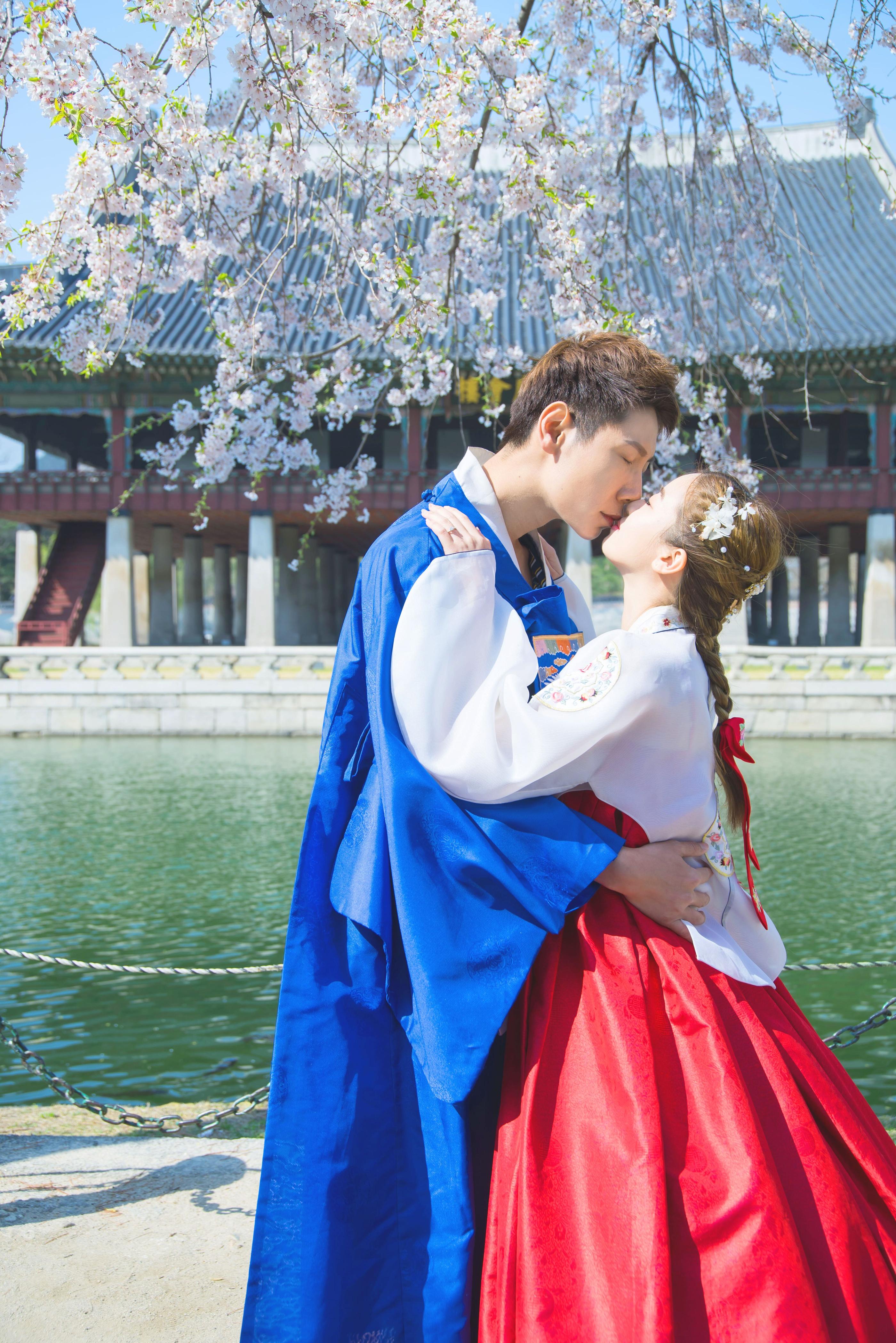 桜の木の下で韓服を着たカップルが見つめ合う風景