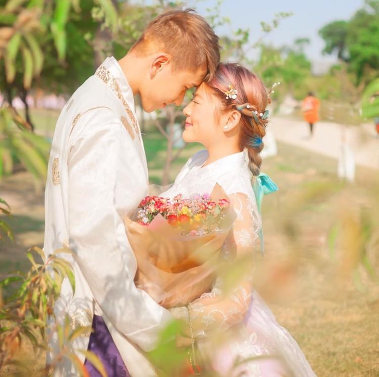 明るい公園で韓服を身にまとったカップルが抱擁するシーン