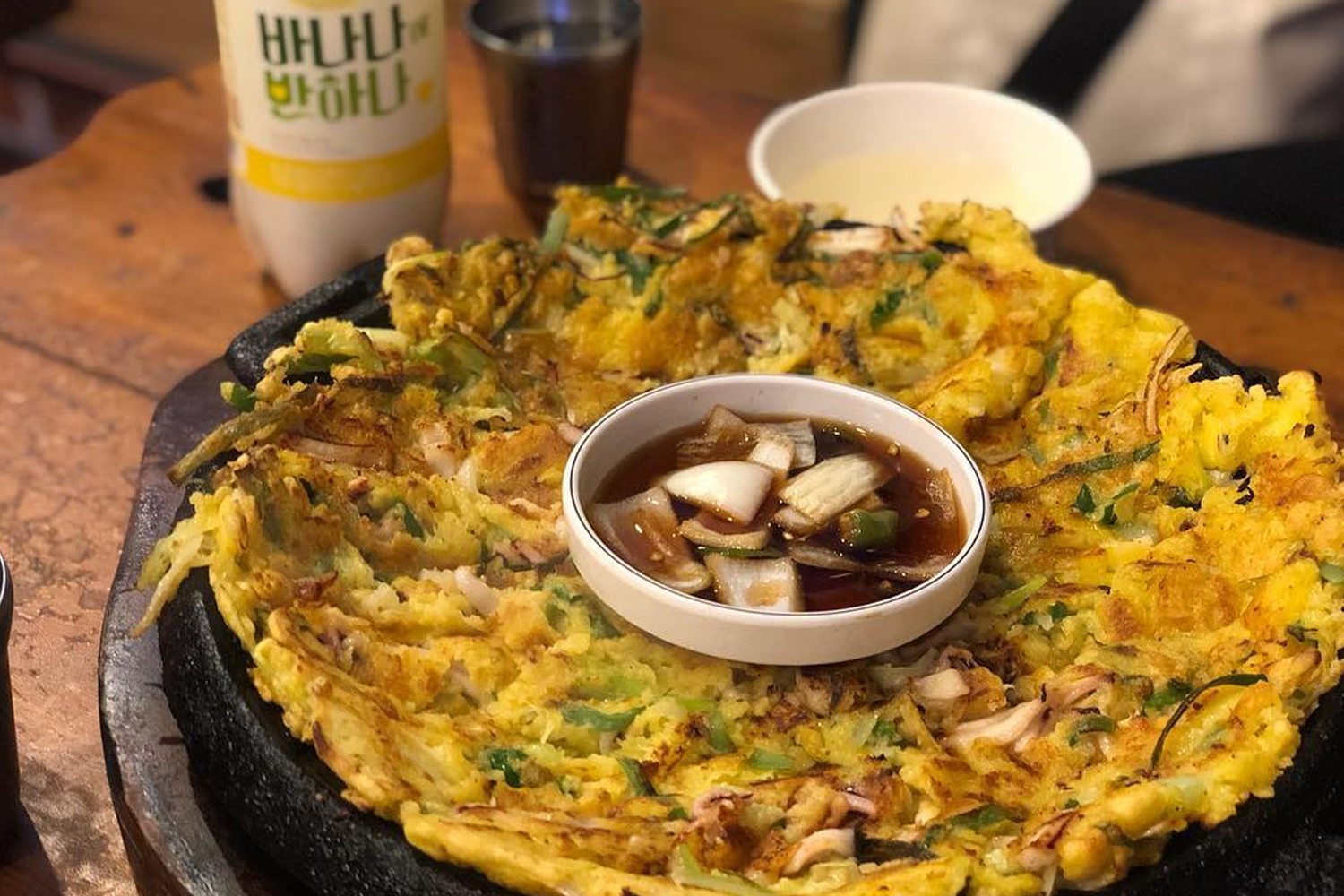 一盤上桌的韓國葱餅，旁邊放著韓國傳統米酒，這是韓國人喜愛的搭配，享受午餐或晚餐的最佳選擇。