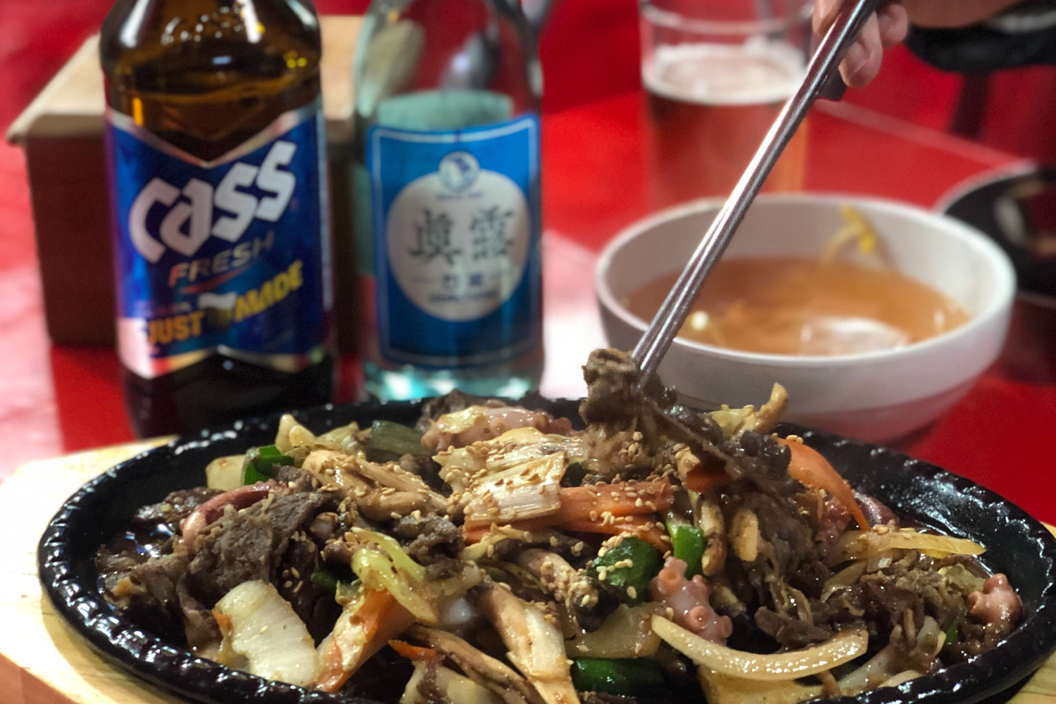 韓國布帳馬車熱門美食燒酒與辣炒牛肉，從杯中倒出來的燒酒和餐桌上的食物，是夜間餐飲的完美搭配。