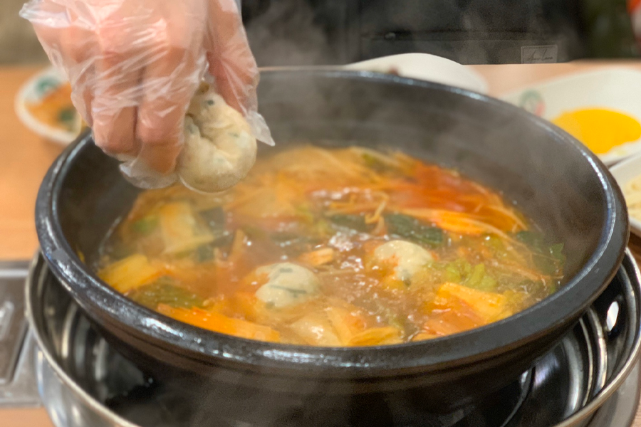 韓國首爾聖經餃子店，廚師正在下手工餃子於鍋中烹煮，保持餃子的完整形狀。