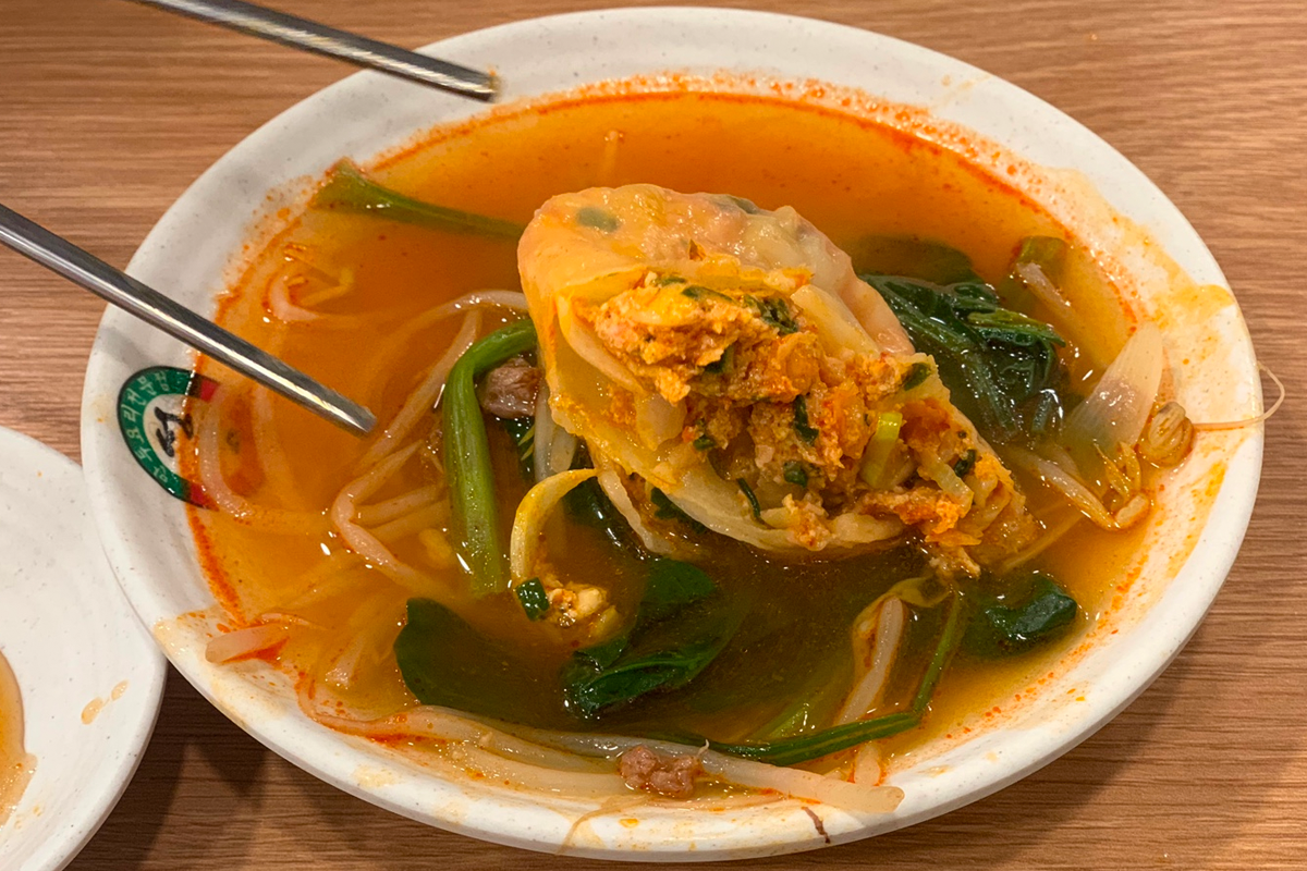 煮熟的餃子在火熱的湯中被盛起，外皮光滑，湯汁濃鬱。