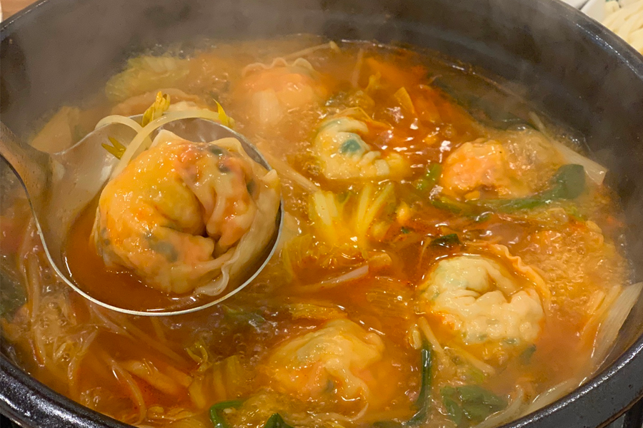 韓國首爾聖經餃子店的紅湯餃子鍋，湯頭呈現鮮紅色，內含泡菜和豬肉餃子。