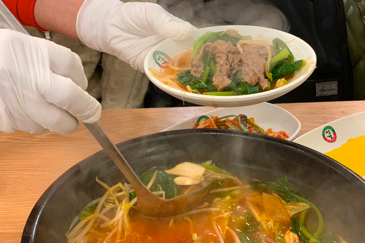 一鍋正在烹煮中的熾熱湯底，蓋子上沾滿了湯氣，透出朦朧的食材影像。