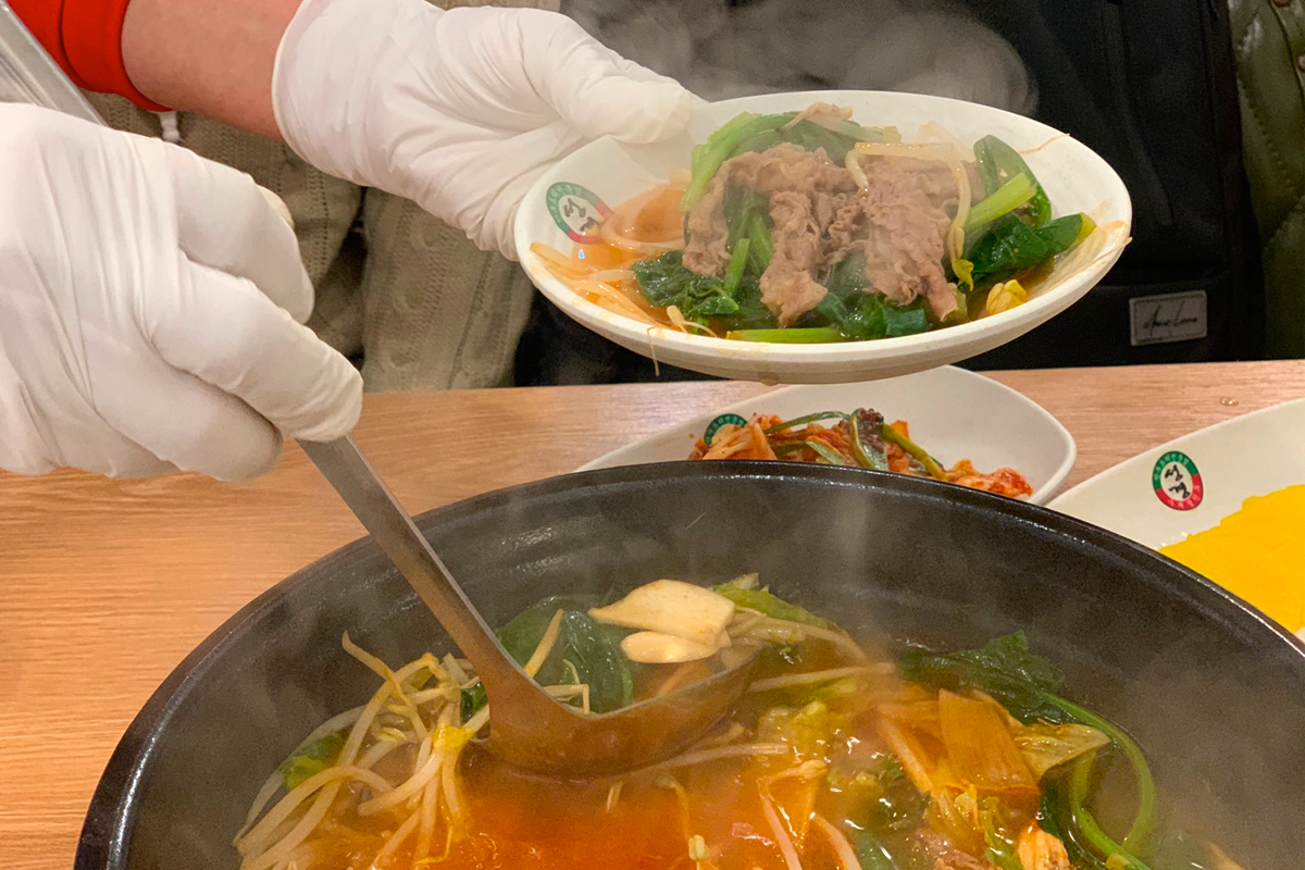 一鍋正在烹煮中的熾熱湯底，蓋子上沾滿了湯氣，透出朦朧的食材影像。