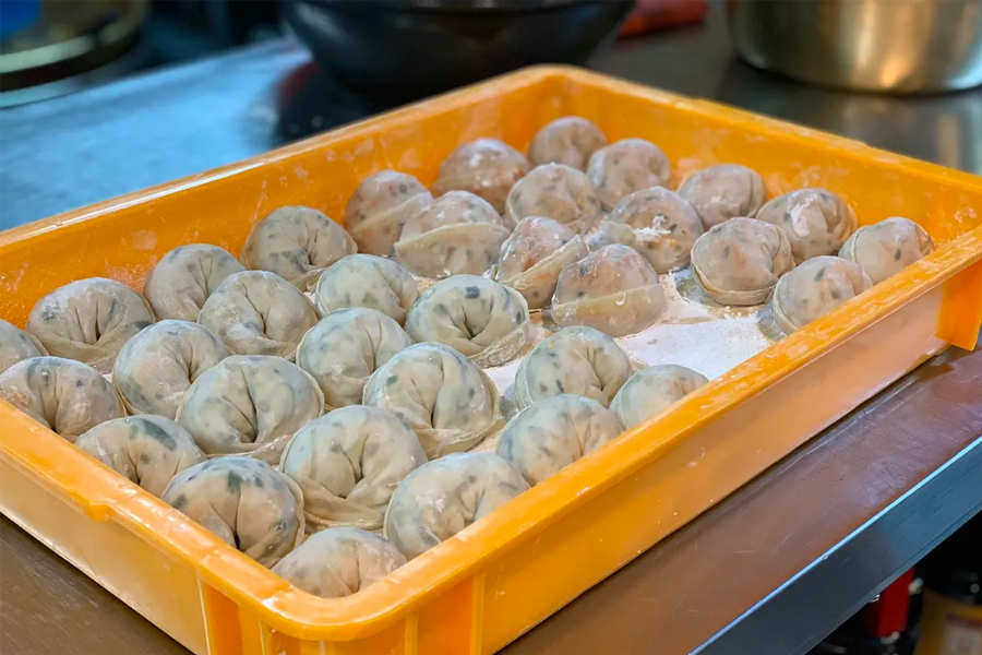 韓國首爾聖經餃子店內的員工，正在精心製作手工泡菜餃子。」