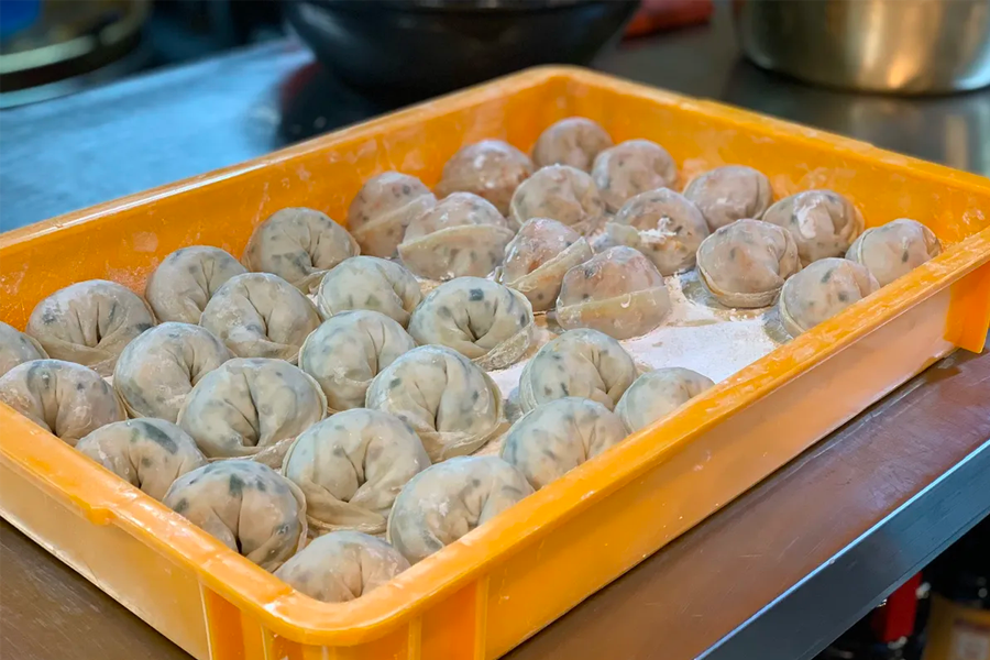 韓國首爾聖經餃子店內的員工，正在精心製作手工泡菜餃子。」