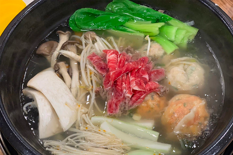 韓國首爾聖經餃子店的紅湯餃子鍋，熱騰騰的泡菜和餃子正在煮熟。