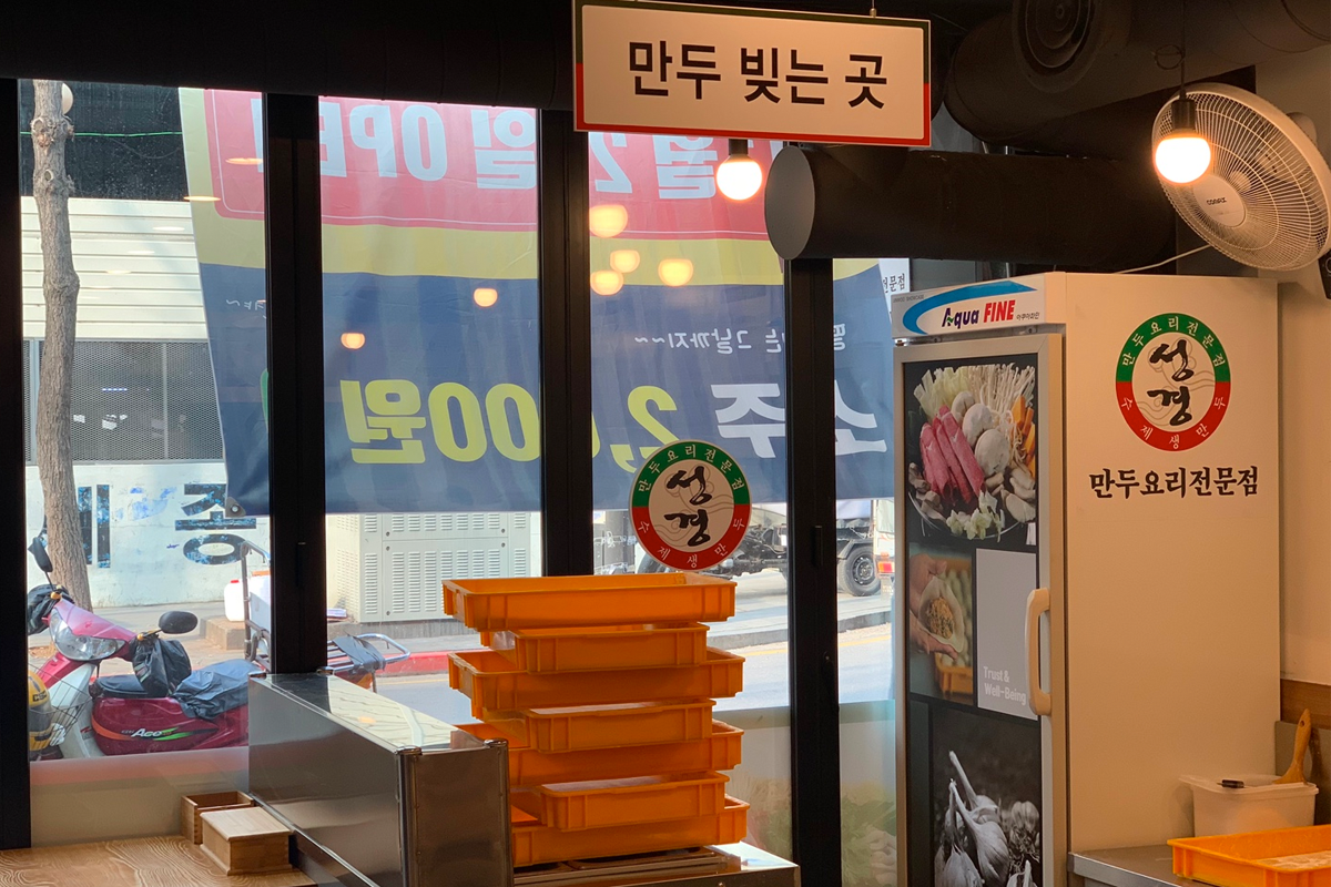 一塊剛剛煮好的牛肉片，被夾起並放在沾滿醬油的碟子上，準備享用。