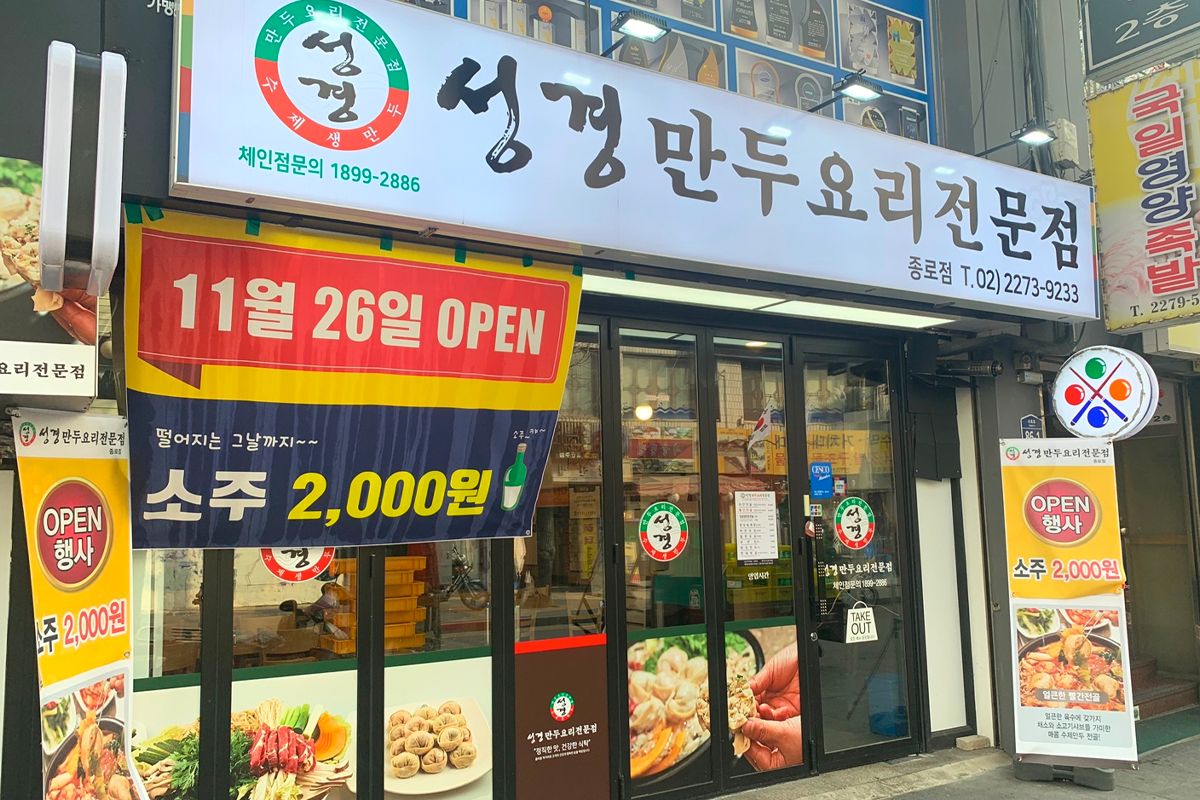 聖經餃子料理專門店的入口，展示了菜單和各種特價促銷信息，以及開店日期的韓文標誌。