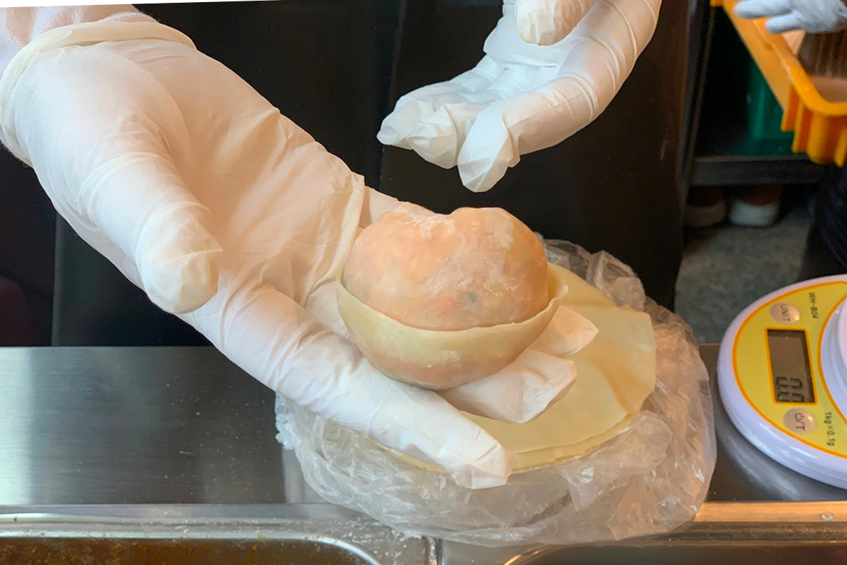 工作人員在秤量手工餃子的餡料，每手工包出的餃子都經過精確測量。