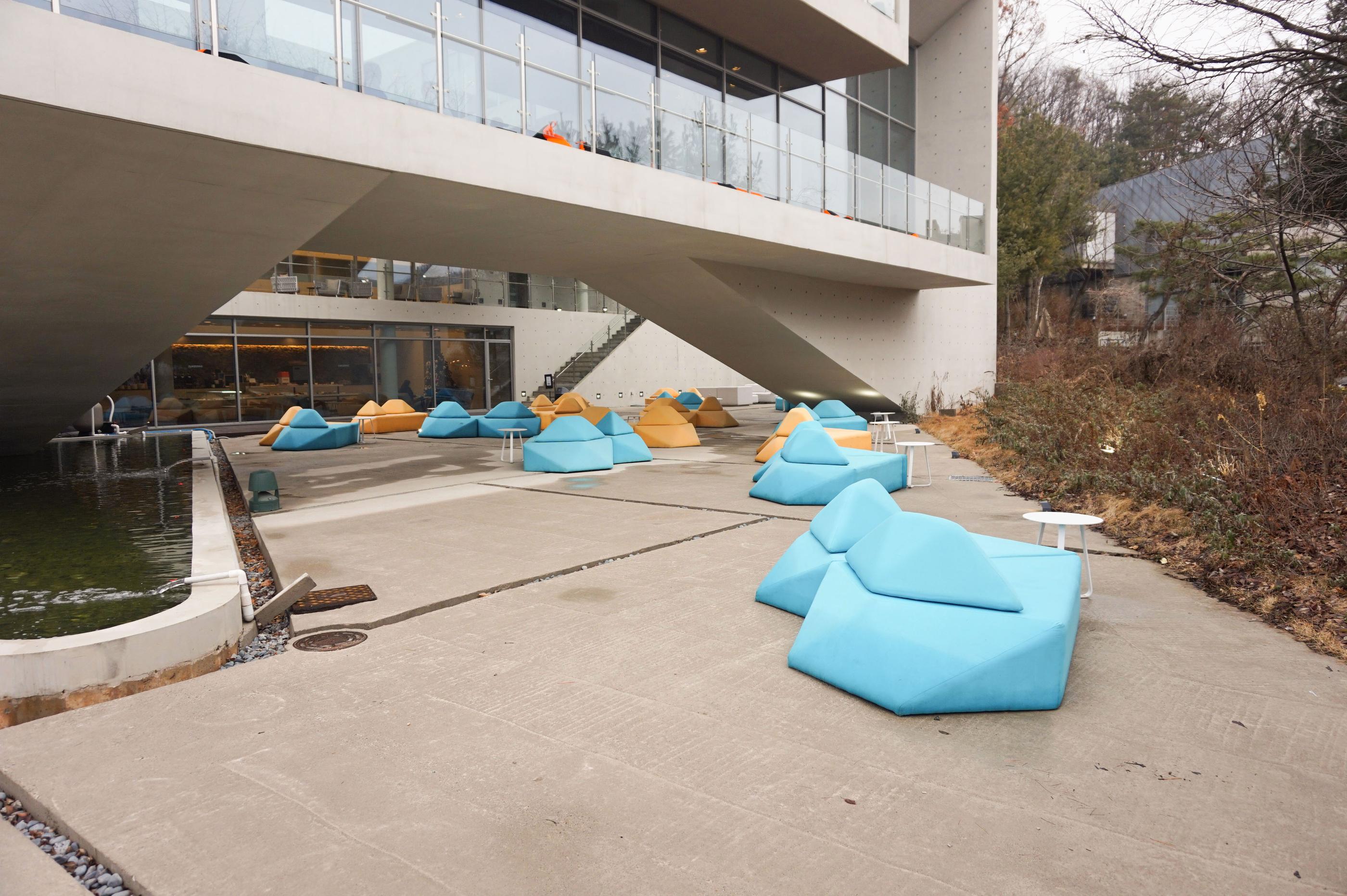 Offener Hofbereich von GARDENUS in Paju mit ansprechenden bunten Sofas und moderner Architektur.