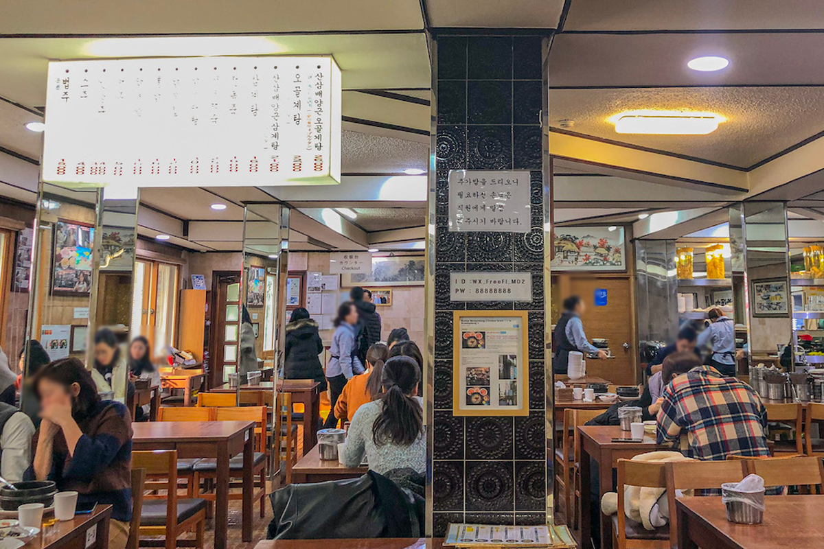 百濟蔘雞湯餐廳內部，設有木質桌椅，顧客正享用食物，環境舒適和傳統。