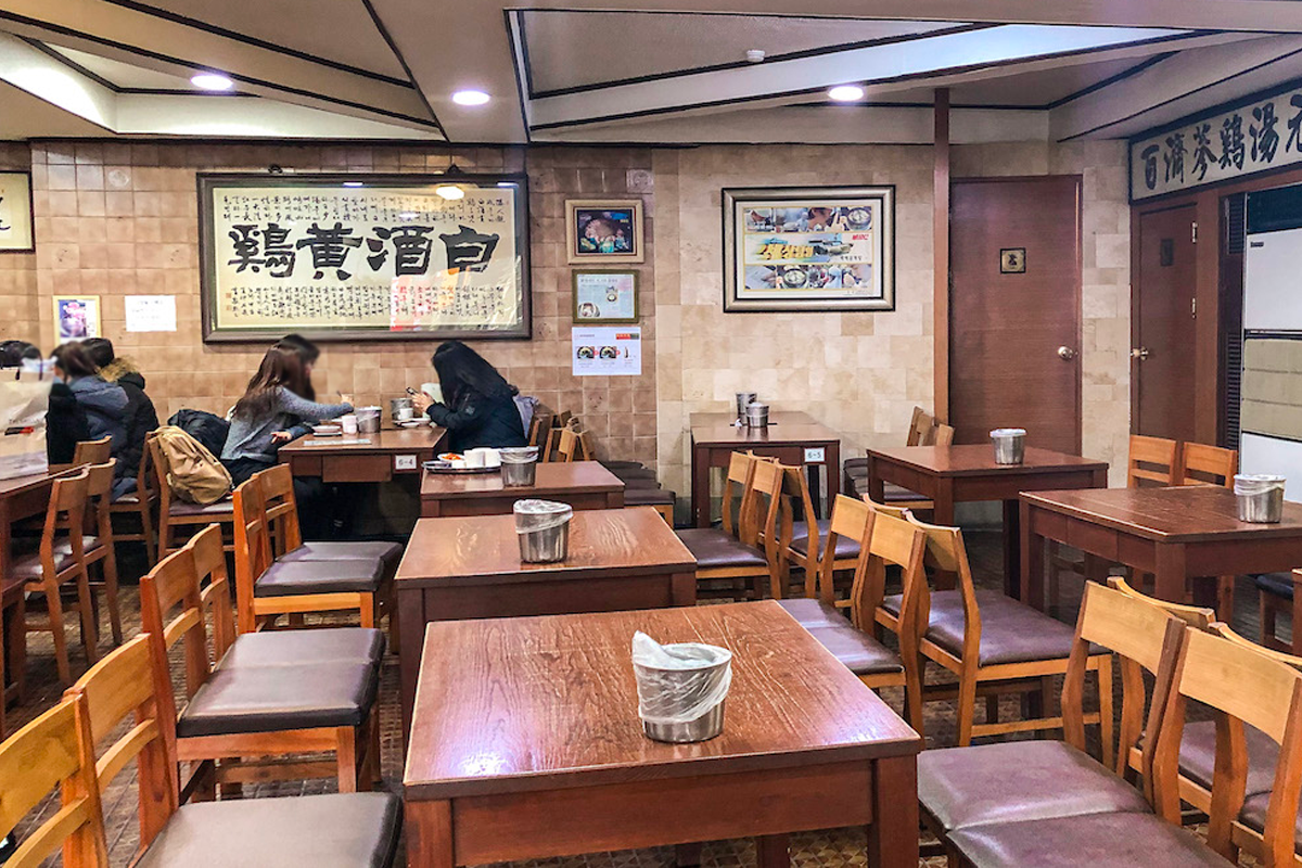 一家傳統的韓國餐廳內部，設有木質桌椅，牆上掛著古典的韓國書法藝術品。