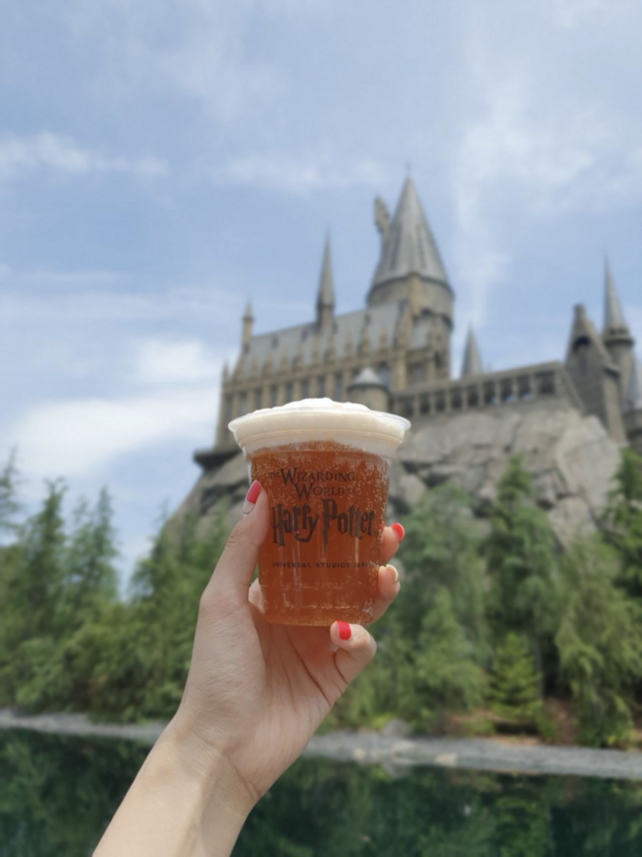 手持哈利波特童話世界的奶油啤酒，在哈利波特城堡前面，享受盛夏假期的快樂時光。