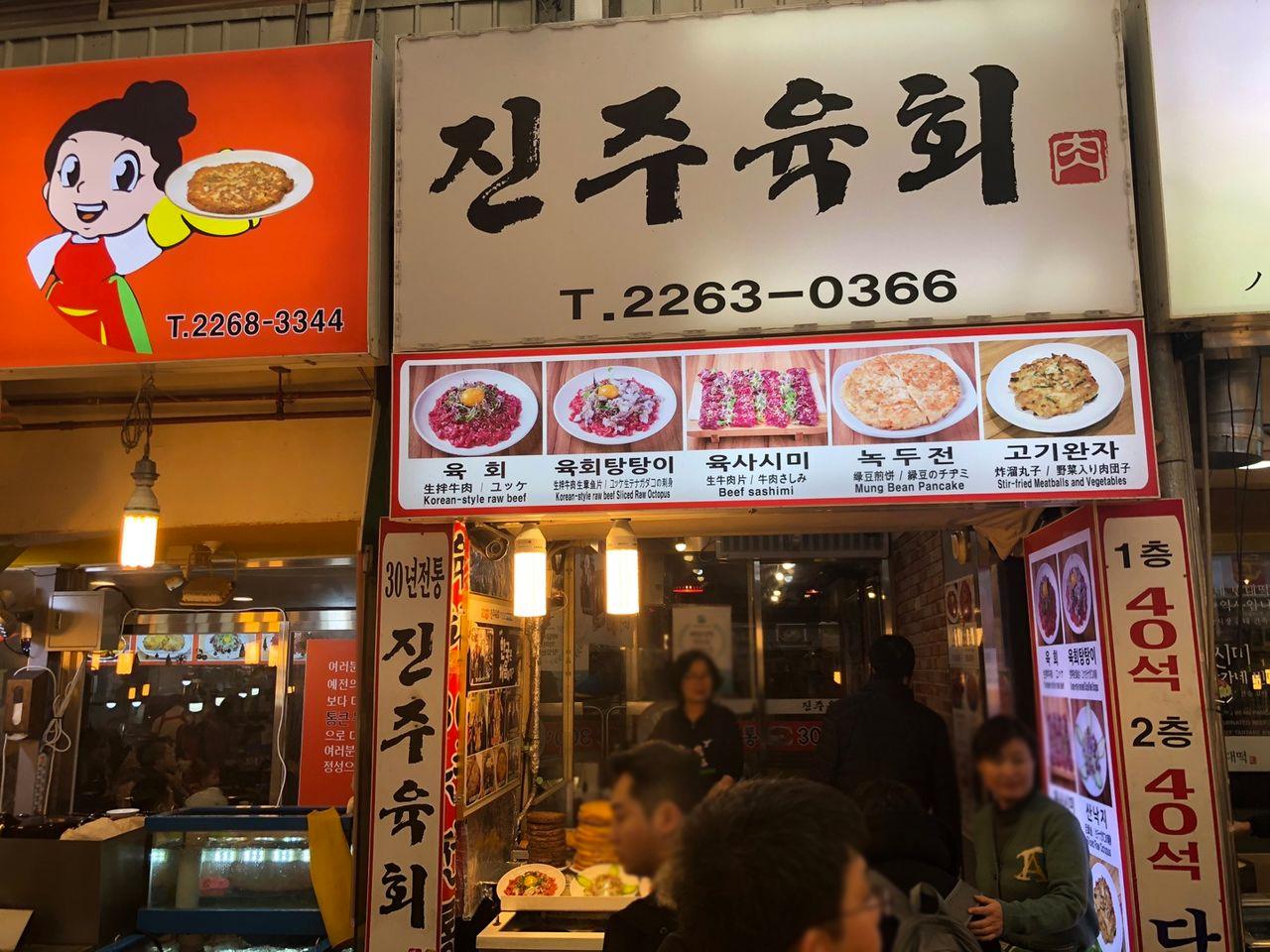 晉州肉膾餐廳入口，招牌上陳列著餐點圖片和聯絡電話