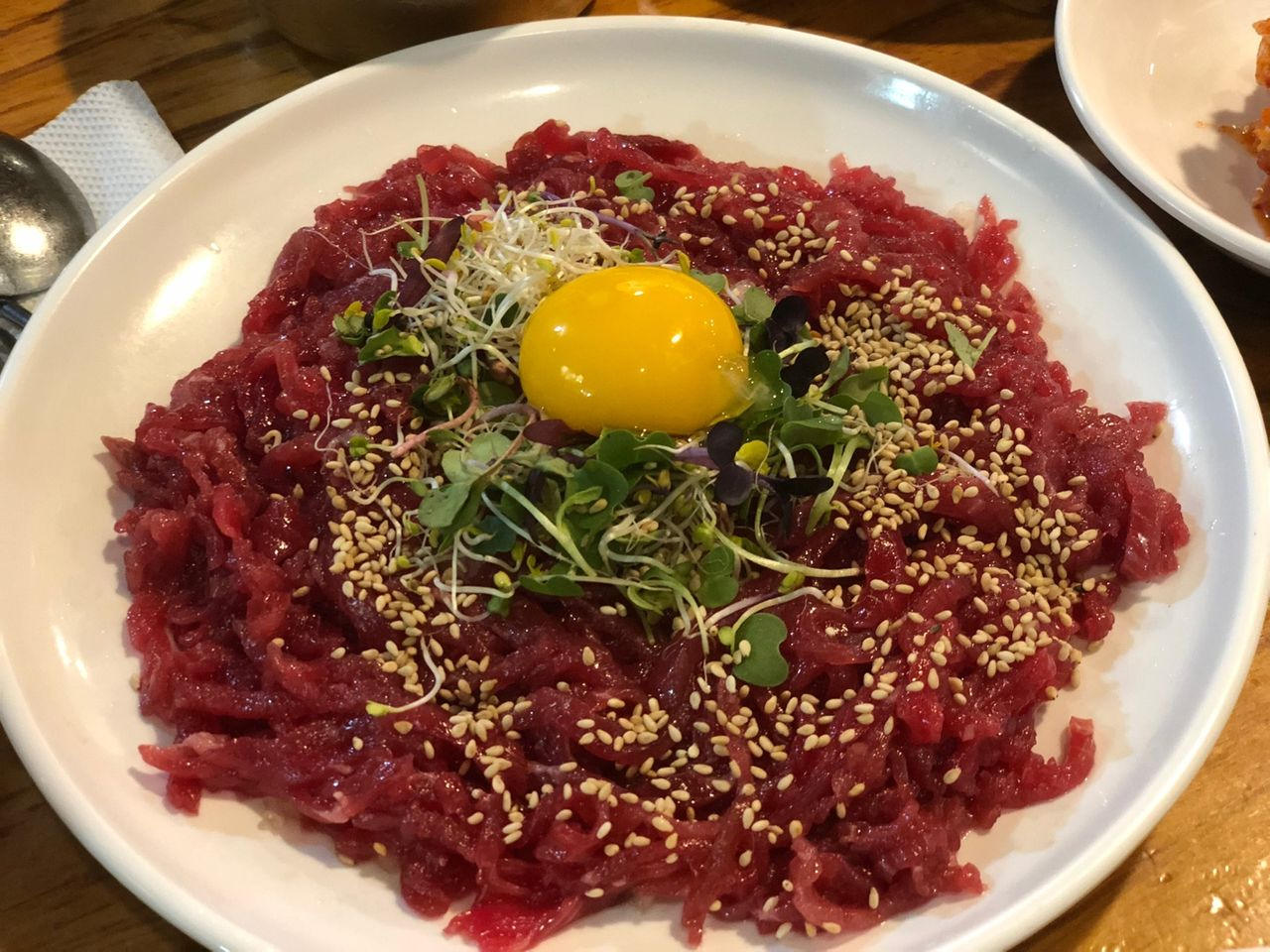 韓国の伝統的な料理、ユッケ。新鮮な赤身の牛肉が盛られ、上には卵黄とゴマがトッピングされている美しい一皿。ソウルの晋州ユッケ店で提供される、一度食べたら忘れられない味の人気メニュー。