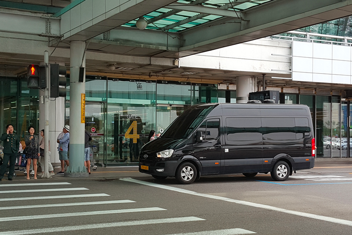 大型車輛停在韓國仁川機場外提供接送服務,強調便捷舒適的旅遊體驗。