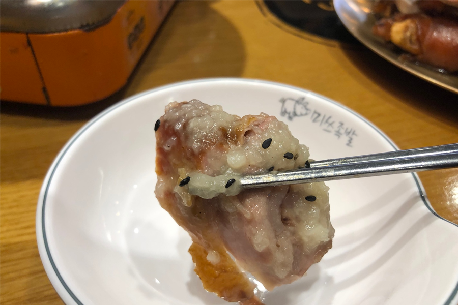 手持正在享用的豬腳，裡邊包著豐盈的肉，滿足燒烤愛好者的美食選擇。