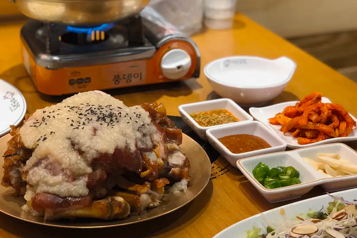 餐桌上的豬腳料理，搭配多樣的小菜和調味料，適合2-3人的分享餐。