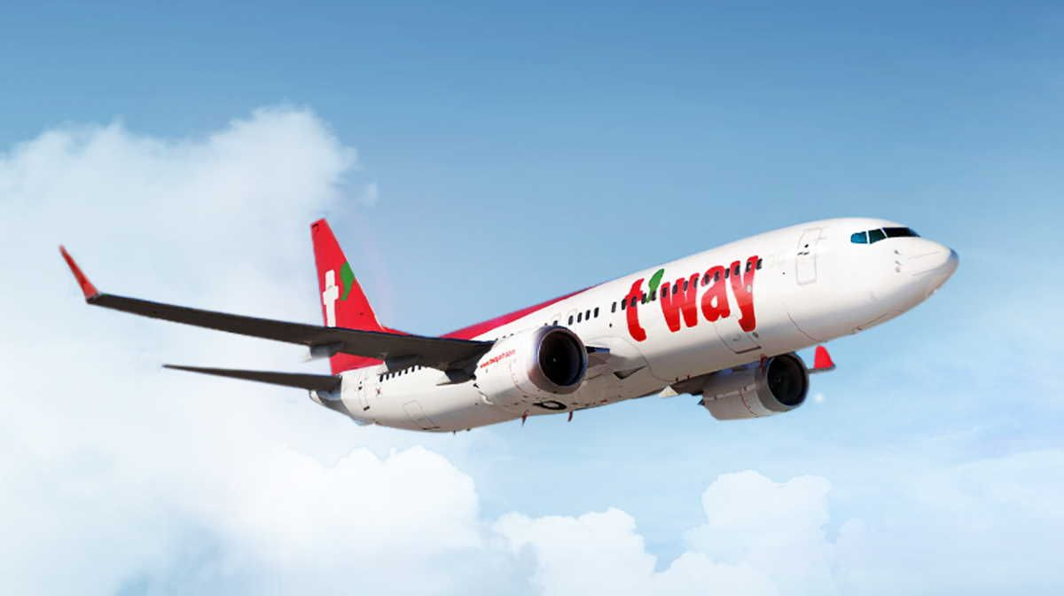 เครื่องบินของ T'way ในท้องฟ้าสีฟ้าเฟื่องฝา พร้อมโลโก้ของสายการบิน T'way บนหางเครื่องบิน 