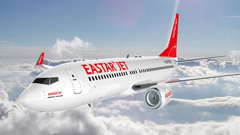 เครื่องบินของ Eastar Jet กำลังบินผ่านท้องฟ้าเคลียร์ด้วยโลโก้สีแดงบนหางเครื่องบิน 