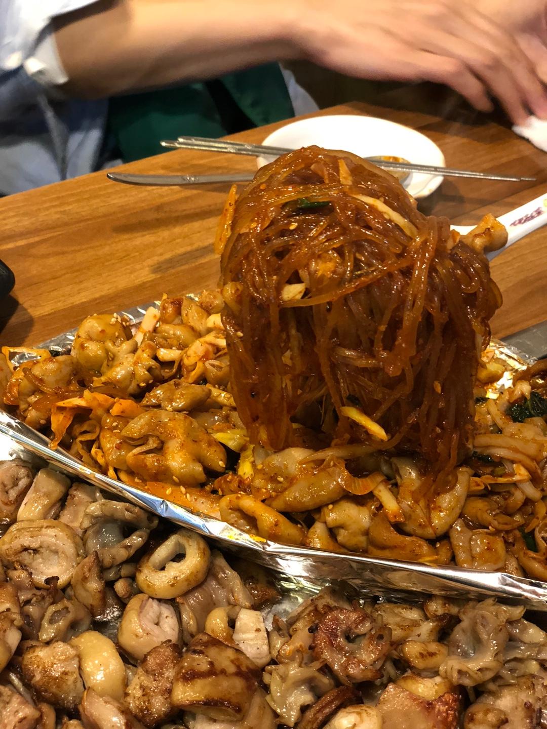 在Jungbu家烤腸店，充滿烤腸和冬粉的圍桌，展現了這裡人群彙聚的熱鬧景象。