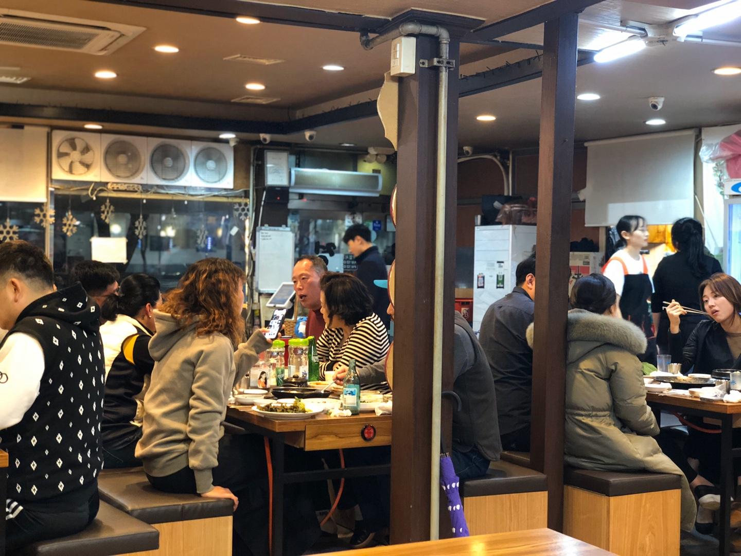 Jungbu家烤腸店內，擁擠且熱鬧的食客人潮，展示了此店的人氣和受歡迎程度。