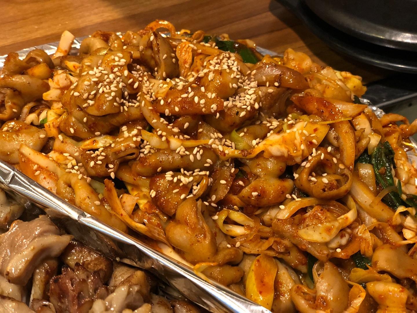 炒めた豚の小腸と野菜が皿に盛られ、韓国料理店ジョンブネコプチャンの名物料理。胡麻が振りかけられ、美味しそうな見た目。往十里駅近くで人気のホルモン料理をお試しください。