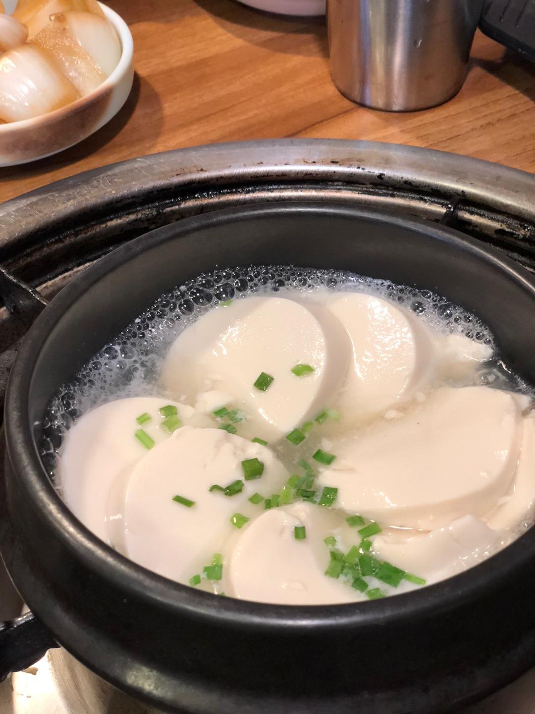 韓式白豆腐鍋特寫，豆腐在鍋中沸騰，表面飄著蔥花替平衡胃口，必要時解膩的美味選擇。
