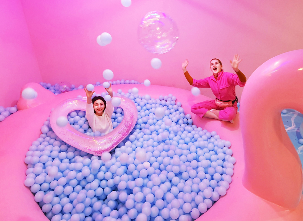 ピンクのボールプールで遊ぶ様子。ハート型の浮き輪があります。ボールプールは青いボールでいっぱいです。